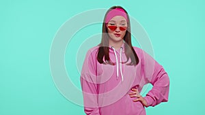 Seductive cheerful positive teen girl in hoodie wearing sunglasses, charming smile, blinking eye