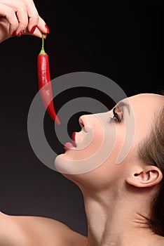 Seductive girl flirting with spicy pepper