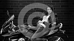 Seductive girl sits on bike on black background with leather jacket