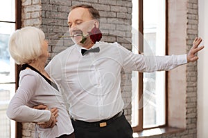 Seductive man tangoing with senior woman in the dance studio