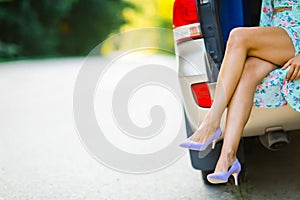 Seductive prostitute with exposed legs sitting in car trunk