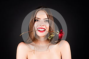 Seductive sensual woman holding red rose with teeth. Woman with naked shoulder and rose flower in mouth on black