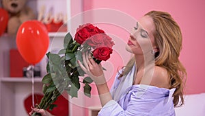 Seductive woman smelling bunch of red roses, bouquet delivery, Valentines day