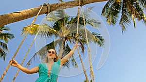 Seductive woman swinging on a swing on a tropical beach, on shores of the turquoise sea. Concept travel, walks, rest in