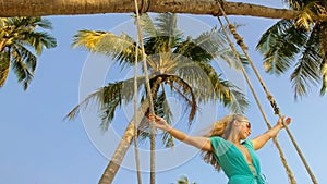 Seductive woman swinging on a swing on a tropical beach, on shores of the turquoise sea. Concept travel, walks, rest in