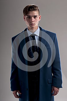 Seductive young man wears suit with coat