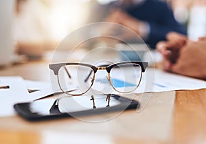 We see everything in a different way as creatives. Closeup of a pair of reading glasses on a wooden table outside in a