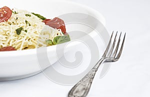 Plate of spaghetti with cherry tomatoes, basil and grated cheese photo