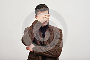 See nothing! Young man covering his face with hand isolated on a white background