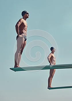 See you at the bottom. Full length shot of two handsome young male athletes standing on diving boards outside.