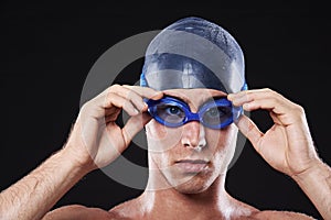 See you in the lane. Studio portrait of a young male swimmer with goggles and cap.