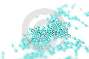 Seed beads of aquamarine color on white surface close up