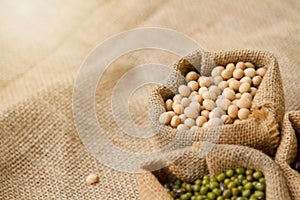 Seed of soy beans in fabric bag on linen background