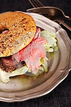 Seeded bagel with steak on tin plate