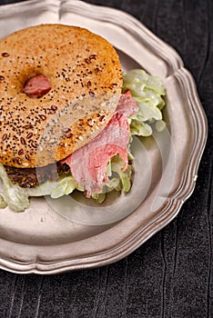 Seeded bagel with steak on tin plate