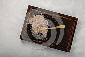 Seeds chia white in golden spoon on wooden cutting board, top view. Grey background, copy space. Chia contains a large array of