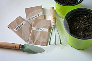 Seeds of herbals in paper bags, garden tools for home. green plastic pots. Planting on balcony, during quarantine. Close up