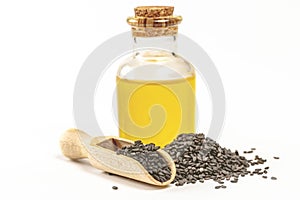 seeds with seed oil in a glass bottle and a wooden spoon