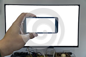 Seeing only through a screen concept. Man holding phone in front of a tv