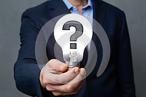 Seeking answers person holds light bulb with question mark symbol