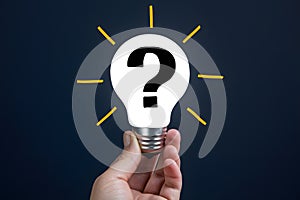 Seeking answers person holds light bulb with question mark symbol