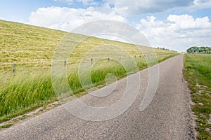 Seemingly endless road along an embankment and a fence