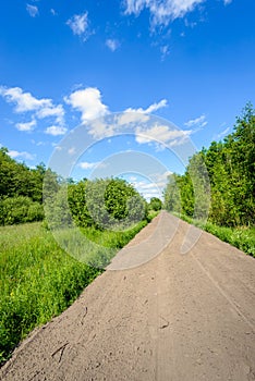 Seemingly endless sandy road in a rural area in summertime