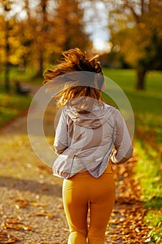 Seen from behind modern woman in fitness clothes in park jogging