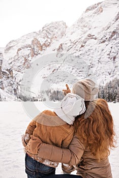 Seen from behind mother pointing child on snow-capped mountains