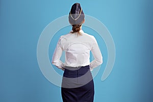 Seen from behind stylish air hostess woman on blue