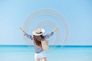 Seen from behind stylish woman on ocean coast rejoicing photo