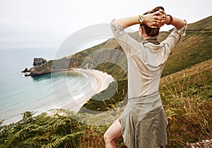 Seen from behind woman hiker enjoing ocean view landscape