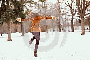 Seen from behind woman rejoicing outside in city park in winter