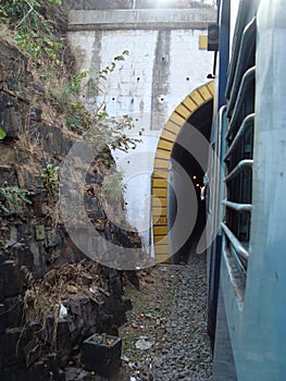 Seen of train running between stone mountains and going out from tunnel