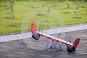 Seesaw swing in big yard with soft rubber flooring on sunny summer day photo