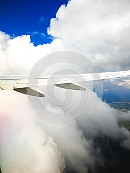 Segment of a airplane wing high in the sky between the white clounds photo