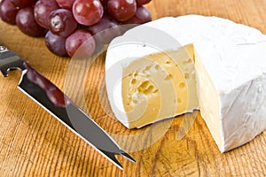 Segment of brie with grapes and a knife photo