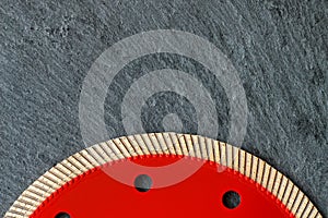 A segment of a red diamond blade for cutting granite against a background of gray granite