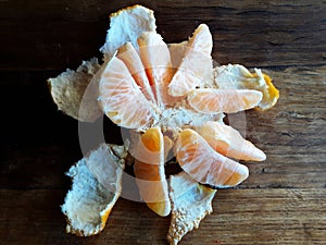 Segments of peeled mandarin fruit on wooden table