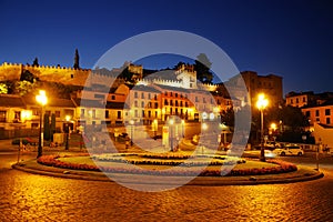 Street night scene in Segovia - Plaza de la Artilleria and the ancient city walls in the background photo