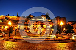 Street night scene in Segovia - Plaza de la Artilleria and the ancient city walls in the background photo