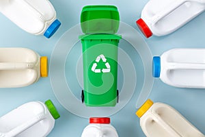 Segregation of plastic waste, green garbage bin and plastic bottles on a beautiful blue background, environmental concept
