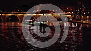 Seine river with cruise boat illuminated at night in Paris, France