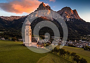 Seis am Schlern, Italy - St. Valentin Church and famous Mount Sciliar mountain with colorful clouds, blue sky and warm sunlight photo