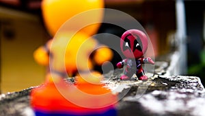 Two McDonald's toy Deadpool and orange spiderman having a final fight on the road