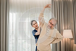 Select focus to old man. Professional Asian young woman physiotherapist helping senior men stretch arm and back for physiotherapy