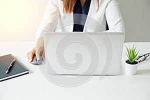 Selected focus laptop with woman hand holding on mouse and working on white desk modern office