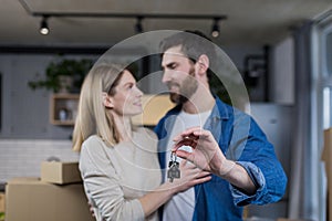Selected focus, married couple man and woman happy together, hugging, holding the keys to their new apartment, housewarming, close