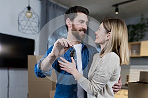 Selected focus, married couple man and woman happy together, hugging, holding the keys to their new apartment, housewarming, close