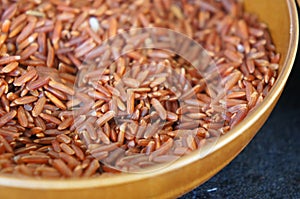 Selected focused of raw brown rice or paddy seed in brown ceramic bowl.